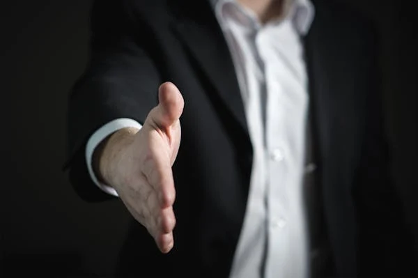 A businessman extending his hand in a gesture of agreement, symbolizing successful negotiation and mutual understanding.